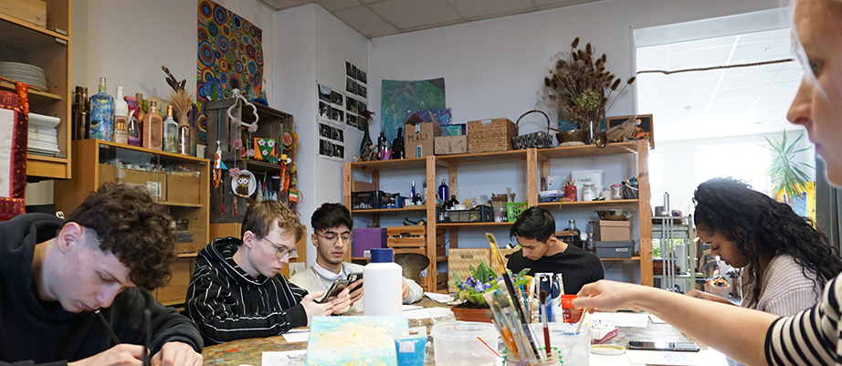 Sechs Teilnehmende sitzen in einer Kreativwerkstatt am Tisch.