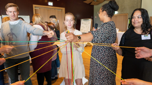 Teilnehmende ziehen gemeinsam an F&auml;den