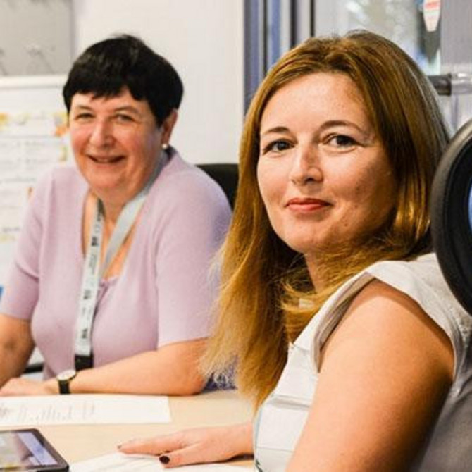 Vier Personen sitzen mit einem Tablet an einem Tisch