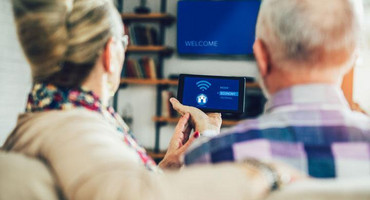 Seniorin und Senior gemeinsam auf einem Sofa mit Remote control für Smarthouse