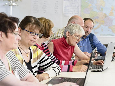 Gruppe älterer Frauen und Männer beim gemeinsamen Lernen am Computer