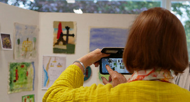 Frau fotografiert mit dem Handy in einer Ausstellung