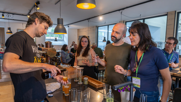 Teilnehmende an der Biertheke, ein junger Mann schenkt Bier aus