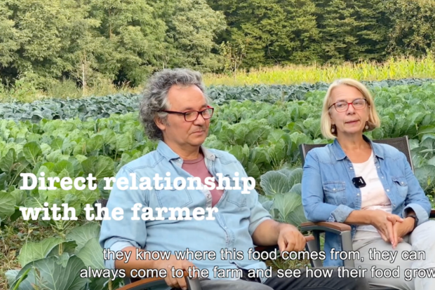 Ein Mann und einen Frau sitzen auf einer Bank vor einem Feld