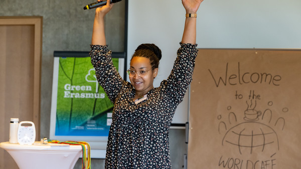 Moderatorin hebt lachend die Arme in die Luft