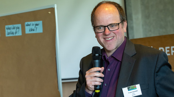 Freundlich l&auml;chelnder Mann mit Mikrophon