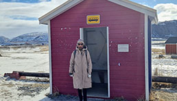 Eine Frau steht vor einem kleinen, roten Bushaltestellenh&auml;uschen