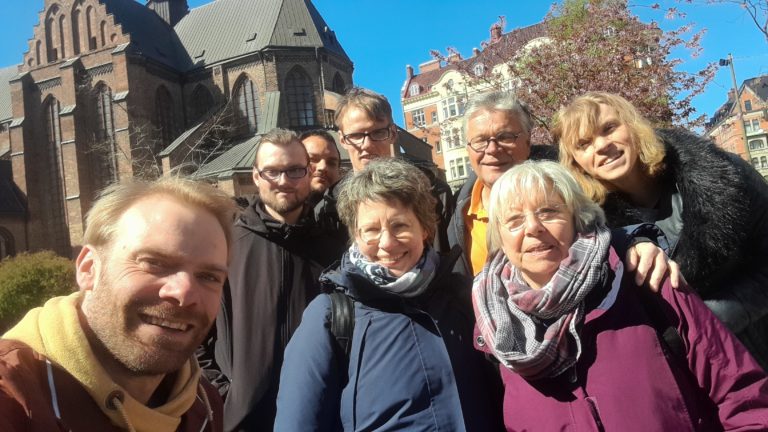 Acht Personen stehen vor einer Kirche