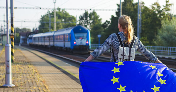 Junge Frau mit Europafahne auf einem Bahnsteig