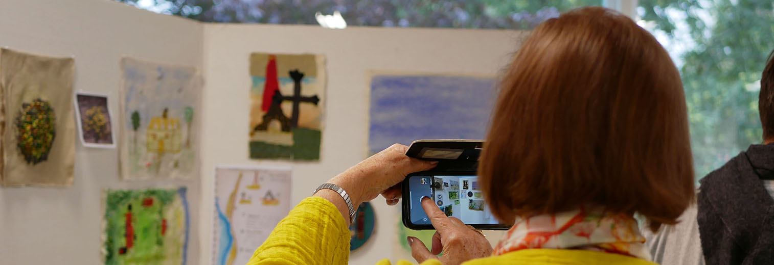 Eine Frau fotografiert mit dem Handy in einer Ausstellung