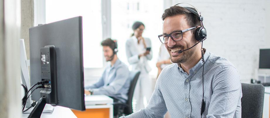 Mann sitzt vor PC mit einem Headset auf