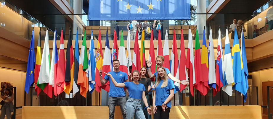 5 Jugendliche vor EU-Flaggen