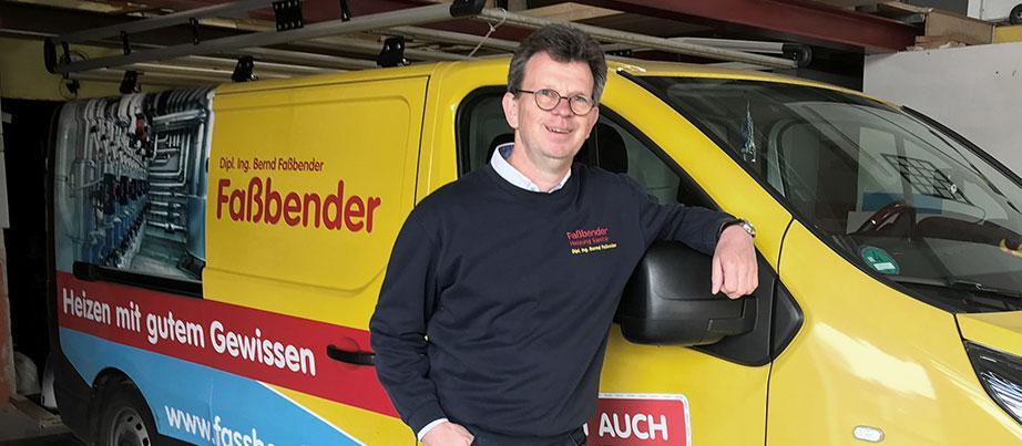 Firmenchef Faßbender angelehnt an einen Firmenwagen mit der Aufschrift Faßbender