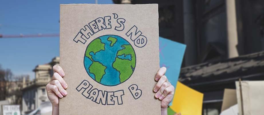 Person hält Protestplakat, auf dem "There's no planet B" geschrieben steht