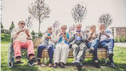 Ältere Menschen mit Smartphone auf einer Bank