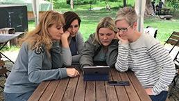 Vier Frauen sehen sich etwas auf einem Tablet an