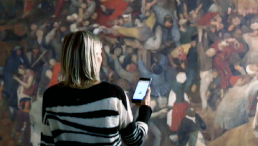 Frau mit Handy vor einem Gemälde