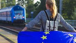 Junge Frau mit Europaflagge am Bahnhof