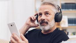 Mann mittleren Alters hört ineressiert Podcast
