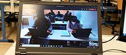 Ein Bildschirm zeigt Schülerinnen und Schüler beim Lernen