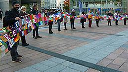 Projektpartnerinnen und -partner vor dem EU-Parlament mit dem 18 m langen Schal der Verbundenheit.